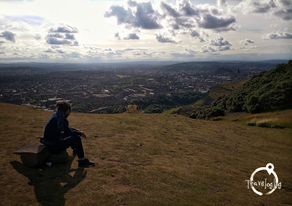 スコットランド：エジンバラ：裏山の黄金色の丘から街を眺める男性